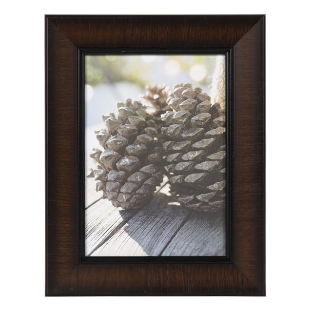 hometrends Lynnwood Smoked Cognac Picture Frame holding a 5" x 7" photo of pine cones on a wooden surface, featuring a rich dark cherry finish with glass protection, suitable for horizontal or vertical display with included hangers or easel, often used as a personalized gift for home or office décor.
