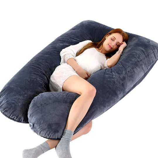 BABYDISE Pregnancy Maternity Pillow, a U-shaped full-body pillow designed for pregnant women, shown in use by a person reclining comfortably. The pillow is oversized, measuring 130x70 cm, and provides support for the head, neck, shoulders, back, legs, and ankles. Made with 100% hypoallergenic PP cotton, it retains its shape and offers relief from conditions like sciatica, back pain, and poor posture. The dark grey pillow features a removable, washable cover for easy cleaning.
