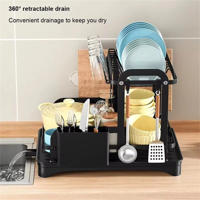 Kitchen Dish Drying Rack, Dish Racks for Kitchen Counter, Large Dish Drainers Rack, Two Tier Black Metal Dish Drying Rack. The image shows a two-tier black metal dish drying rack with a compact design, featuring an upper tier with hooks for hanging utensils and a spacious lower platform for plates, bowls, and cookware. The rack includes a built-in drainage system with a 360-degree retractable drain for efficient water disposal, a bottom drip tray to prevent water accumulation, and a chopstick holder for collecting water droplets. The rack is placed on a wooden countertop next to a sink, showcasing its space-saving and organized design.