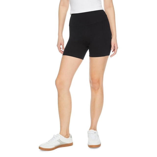 No Boundaries Women's Biker Short in black shown on a model from mid-thigh to waist, made of soft stretch jersey knit with a wide elasticized waistband for comfort, styled with white sneakers and a white top on a white background, suitable for active wear or casual lounging.