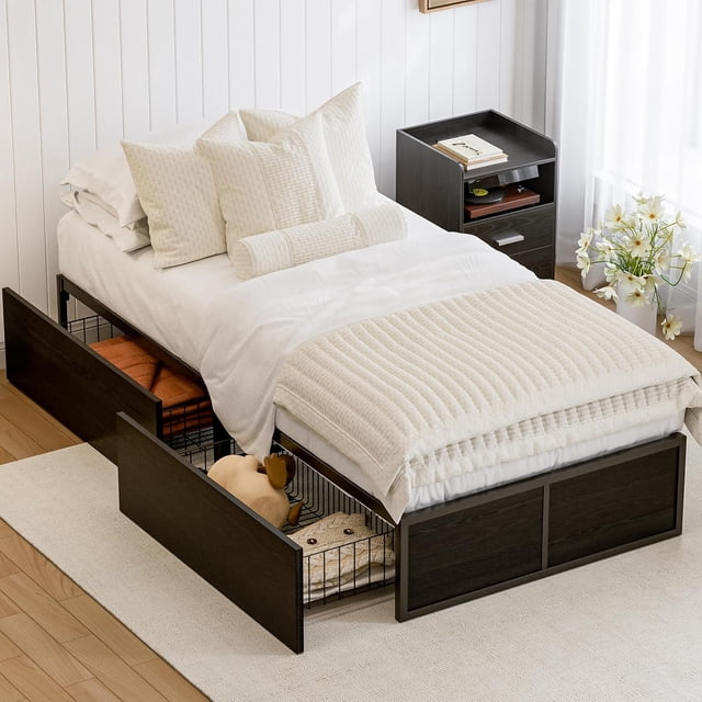GAZHOME Twin XL Bed Frame with 2 storage drawers, black metal platform bed frame with footboard and 9 strong metal slat supports. Designed for bedroom furniture, it features space-saving storage with drawers on wheels that can be placed on either side. The sturdy steel and wood construction supports up to 1000 lbs and includes anti-rust paint for durability. Displayed in a cozy bedroom with white bedding and decorative pillows.