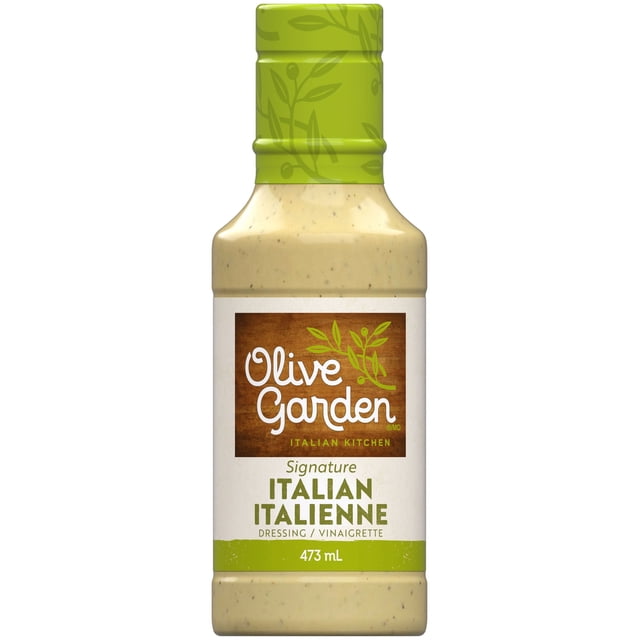 OG LITE DRSG OG ITALIAN DRESSING bottle showing a close-up front view of a 473 mL container filled with creamy light beige Italian salad dressing, topped with a green cap decorated with olive branch patterns, and a label featuring Olive Garden Italian Kitchen branding and bilingual text for Signature Italian Dressing / Vinaigrette, suitable for use as a condiment or salad topping.