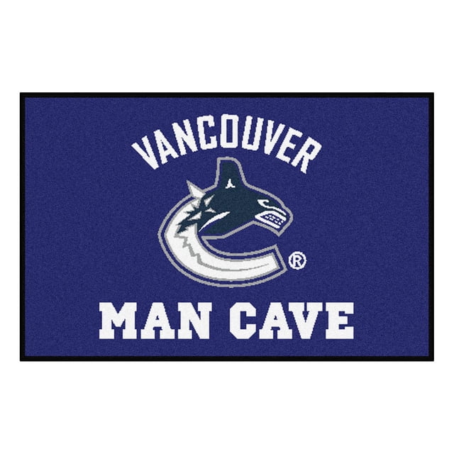 NHL Vancouver Canucks Man Cave Rug with a blue nylon face featuring the team’s orca logo in white and gray, 'Vancouver' above and 'Man Cave' below in bold white letters, measuring 19 by 30 inches, with a non-skid recycled vinyl backing and serged edges, ideal for adding team spirit to a den or office.