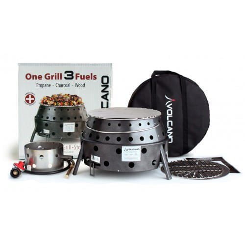 Volcano 3 Cook Stove with Propane Attachment Kit showing a collapsible double wall steel cook chamber with ventilation holes, propane burner attachment, cooking grate, and black carry bag with Volcano logo, displayed with product box highlighting fuel options of propane, charcoal, and wood for versatile outdoor cooking.