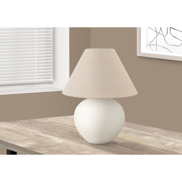 Monarch Specialties Lighting 16-inch table lamp with a cream ceramic globe base and a cream linen empire shade, placed on a light wood side table near a window with white blinds and beige walls, suitable for living rooms or bedrooms.