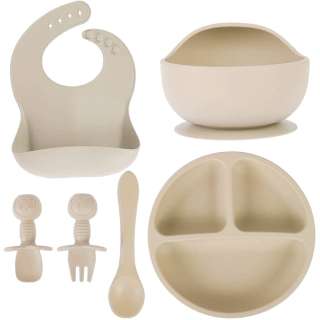 HSHDLDF Set of 6 Baby Feeding Set, including a silicone suction bowl, divided dinner plate, infant bib with food catcher, silicone fork, spoon, and soup spoon. Made from BPA-free, food-grade silicone, this non-slip tableware set is designed for baby-led weaning and self-feeding. The beige set features soft, durable materials with rounded edges for safety and ease of use. Dishwasher, microwave, and freezer safe for convenience.