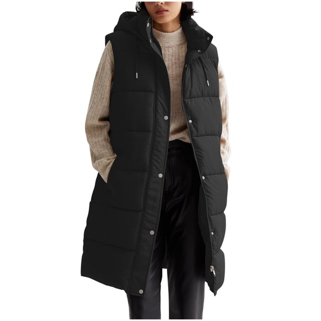 LOVZFMLL Winter Jackets for Women, Long Sleeveless Puffer Vest with Hood and Pockets. This black hooded vest features a long, sleeveless design with a quilted puffer texture. Made from soft polyester, it includes practical side pockets and a front snap-button closure. The vest is styled over a beige sweater and black pants, suitable for casual or daily wear during winter and spring.