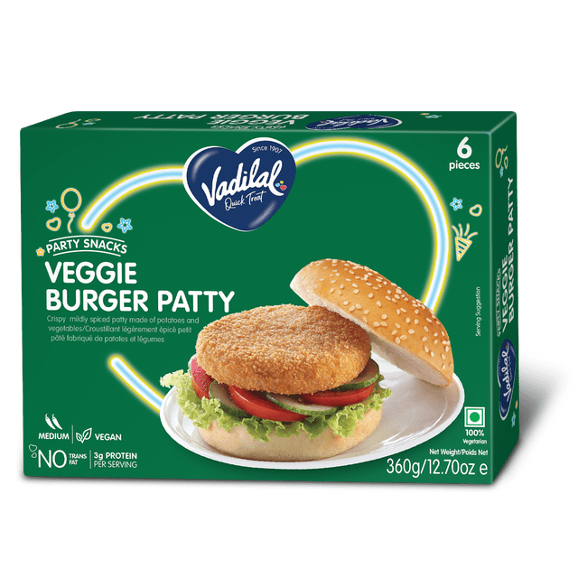 Vadilal Veggie Burger Patty box containing six crispy, mildly spiced potato and vegetable patties. The green packaging shows the Vadilal heart logo and a serving suggestion of a veggie burger with lettuce, tomato, and cucumber in a sesame seed bun. It is vegan, medium spice, contains no trans fat, and provides 3g protein per serving, weighing 360g (12.7 oz).
