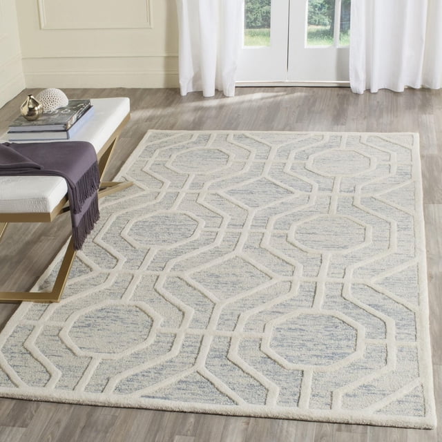 Safavieh Cambridge Johan Geometric Area Rug in a bright room with light wood flooring, featuring a hand-tufted wool texture in grey and cream with a raised geometric pattern of octagons and diamonds, ideal for modern home or office decor and often used as an accent rug.