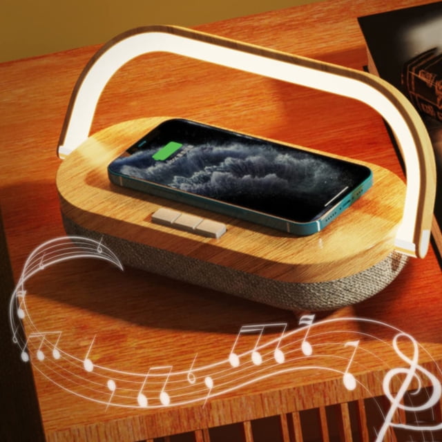 Wireless Charging Lamps - Bluetooth Speaker Bedside Table Lamp with a Nordic woodgrain pattern base and a curved LED light bar. Features include 3-level touch dimming, wireless charging for Qi-enabled devices, Bluetooth 5.0 speaker with 360-degree surround sound, and a 270-degree adjustable phone holder. The lamp is shown on a wooden surface with a smartphone wirelessly charging on its base, accompanied by musical notes symbolizing the speaker functionality.
