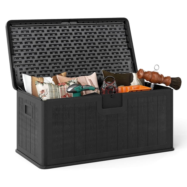 Costway Storage Box with Lockable Design & Gas Strut Handle 2 Person Bench Garden Organizer. A black 100-gallon deck storage box made of durable HDPE material with reinforced aluminum alloy corners, featuring a lockable lid and gas strut for easy opening and soft closing. The box is shown open, holding patio cushions, garden tools, and pool supplies. Ideal for outdoor use as a storage solution and seating for two people in spaces like backyards, porches, and poolside areas.