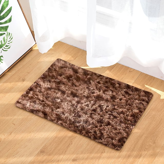 LSLJS Soft Rugs for Living Room, a small washable mini area rug with a non-slip backing, featuring a soft, fluffy texture in a warm brown color. Positioned on a wooden floor near a white curtain, suitable for home decor in bedrooms, living rooms, or entryways. Often used as a pet mat or for adding warmth to small spaces.
