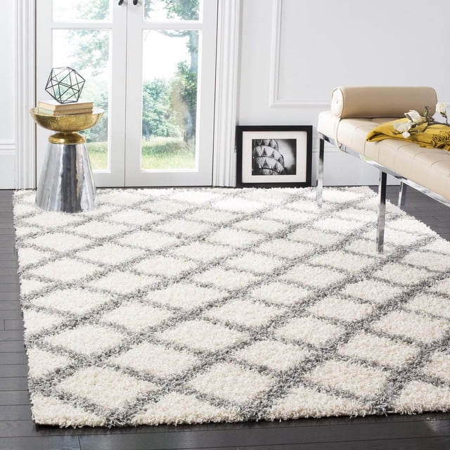 Safavieh Dallas Jerrie Geometric Shag Area Rug featuring a plush white shag texture with gray diamond pattern on dark hardwood floor, styled as an accent rug in a bright room with a beige leather bench and metallic side table, ideal for high-traffic areas.