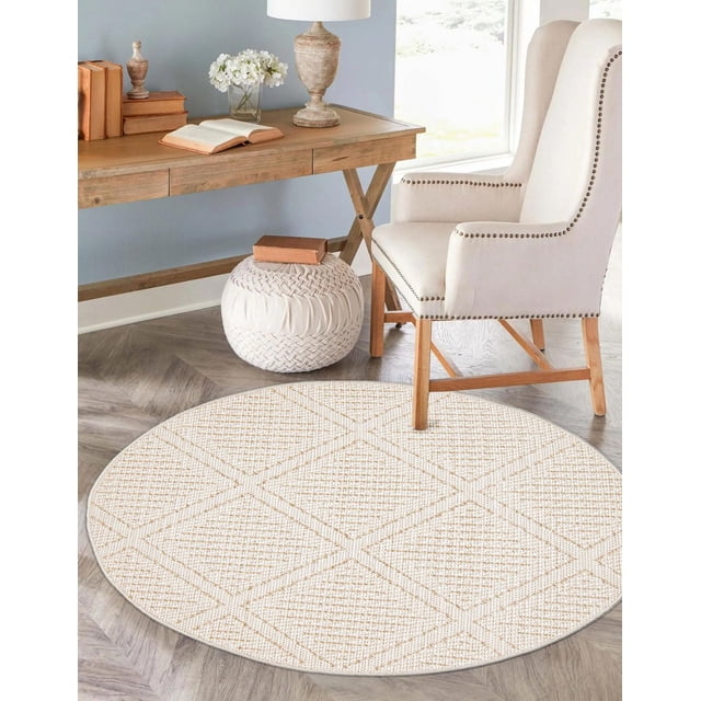 ECARPET Jute Tapis de Style pour Chambre, Salon, Salle à Manger Tosca Collection Présentant un Tapis Rond de Style Jute avec un Subtil Motif de Losanges dans des Tons de Sable et d'Ivoire, Superposé sur un Plancher de Bois Franc à Chevrons. le Tapis Est Placé à Côté d'Un Fauteuil Rembourré beige avec des Pieds en Bois et une Garniture de Clous Décoratifs, un pouf Tricoté avec un Livre sur le Dessus, et un Bureau en Bois avec des Livres, une Lampe et des Fleurs dans une Pièce Lumineuse. Convient aux Zones à Fort Passage et Complète des Intérieurs