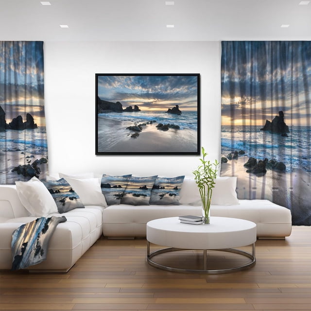 Designart Magnifique Cadre Mural Flottant de Porthcothan Bay ART Représentant une Plage Côtière Rocheuse au Coucher du Soleil avec Ciel Nuageux, Encadré en Noir et Affiché sur un Mur Blanc. le Salon Présente un sofa Sectionnel Blanc avec Coussins Assortis, Rideaux et Jeté Imprimés de la Même Scène de Bord de Mer, Rehaussant le style Nautique. la Toile Est Enveloppée de Coton de Qualité Supérieure avec Encre Résistante à la Décoloration et Arrive Prête à Accrocher.