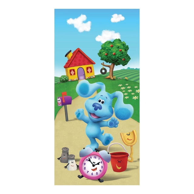Blues Clues "Think Blue" Beach Towel featuring Blue, the blue animated dog, standing on a sandy path with a pink alarm clock, red bucket, yellow shovel, and salt and pepper shakers with faces. The background shows a yellow house with a red roof, a green apple tree with a tire swing, green grass, white flowers, and a blue sky with white clouds. Ideal for drying off after beach or bath time.