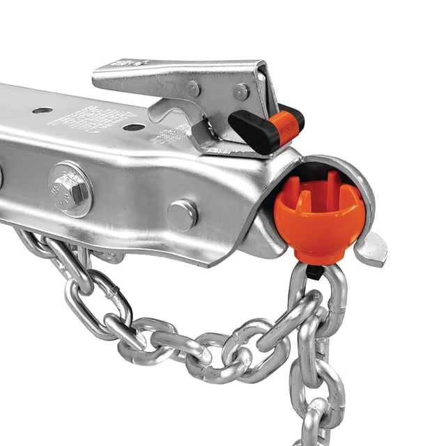 Boule d'Attelage Antivol et Verrou Montrant un Gros Plan d'Un Attelage de Remorque Argenté avec une Boule en polycarbonate orange Vif Insérée pour Bloquer l'Accès à l'Attelage, Sécurisée par une Chaîne Argent Robuste et un Verrou avec une Bande de Visibilité orange sur le Levier de Loquet pour Empêcher le Remorquage de la Remorque.