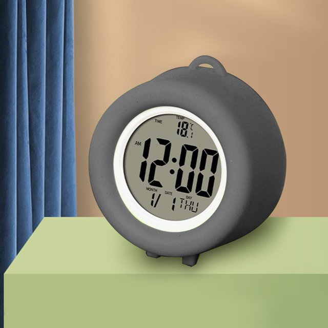 TopLLC Digital Electronic Clock with LED display and stereo digital design in grey. Features include a snooze alarm, 12/24-hour switching, and countdown timer. Compact ABS construction measuring 2.75 x 2.63 x 1.25 inches, powered by two No.7 batteries. Displayed on a green surface with a beige and blue background.
