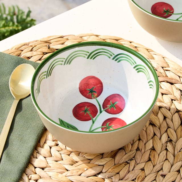 Better Homes & Gardens Bamboo Melamine Cereal Bowl 6.4 Inch with beige exterior and white interior featuring a red tomato vine design and green arches near the rim, placed on a woven placemat with a gold spoon and green napkin, suitable for cereal, yogurt, or small snacks.