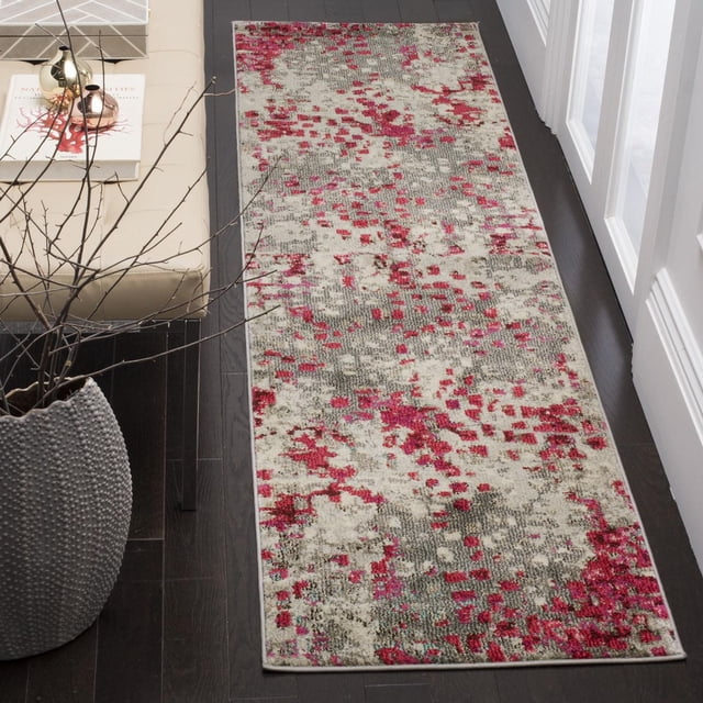 Safavieh Monaco Driskoll Abstract Area Rug with a rectangular shape and abstract red, gray, and beige pattern, made of durable polypropylene with mixed loop pile. Positioned on dark hardwood floor in a hallway next to a beige bench and white door, suitable for adding Bohemian-chic flair to home decor.
