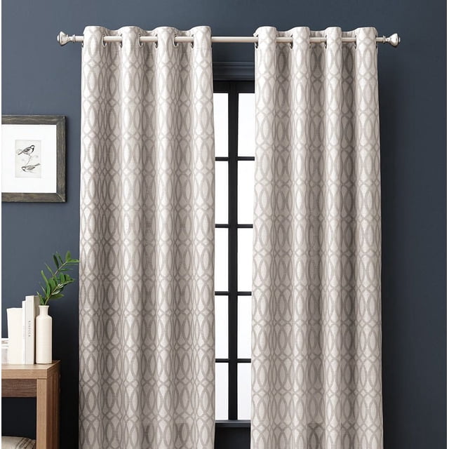 hometrends Jacquard Damask Panel in woven jacquard fabric with a neutral interlocking oval fret pattern, hanging on a white grommet curtain rod against dark blue walls with a framed bird print and wooden side table, ideal for room darkening window treatments and adding texture to living spaces.