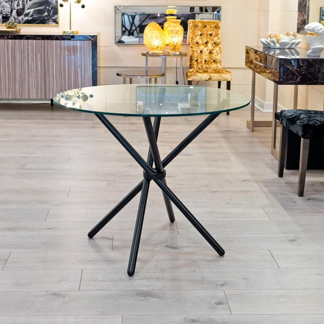 Heavenly Collection Round Glass Dining Table with clear tempered glass top and black matte metal crisscross base, 30 inches high and 39 inches diameter, placed on light wood flooring in a modern dining room with decorative lamps and upholstered chairs, ideal for seating four people.