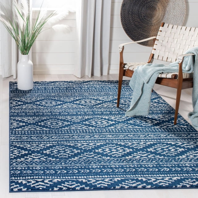 SAFAVIEH Tulum Lakisha Tapis du Sud-Ouest Vieilli avec Motifs Géométriques Bleu et Blanc sur un Plancher de Bois Franc Clair, Décoré d'Une Chaise en Bois avec des Sangles Blanches Tissées et une Couverture Jetée Bleu Pâle, à Côté d'Un vase Blanc avec Herbe de la Pampa dans une Pièce Lumineuse avec des Rideaux Blancs et une Grande Déco Murale Ronde Tissée, Idéal pour Ajouter une Touche Bohème-Chic aux Intérieurs de la Maison.