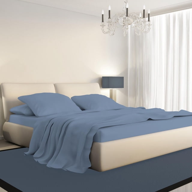 Johnson Home 450 Thread Count Bamboo Bed Sheet Set in blue on a beige upholstered bed with low headboard, including fitted sheet, flat sheet, and pillowcases. The room has white walls, sheer curtains, a blue lamp, a blue rug, and a crystal chandelier, showcasing breathable, hypoallergenic bamboo fabric for year-round comfort.