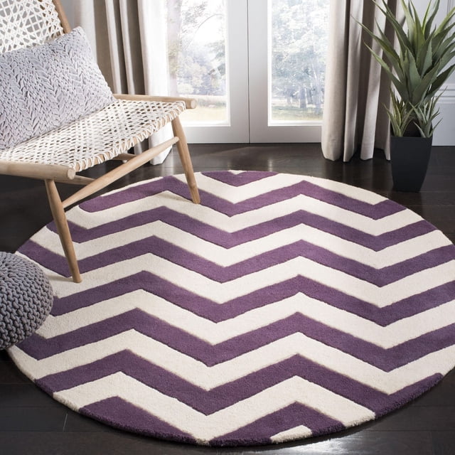 Safavieh Chatham Jake Tapis à Rayures Zigzag, un Tapis Rond en Laine Tufté à la Main à Poil Moyen avec des Rayures Zigzag Violettes et Crème, Placé sur un Plancher de Bois Franc Foncé à Côté d'Une Chaise Tressée avec des Coussins Gris et une Plante en Pot Verte Près de Portes en Verre avec des Rideaux Beiges, Convient à la Déco Contemporaine de la Maison et Ajoute de la Douceur sous les Pieds.