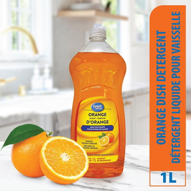 Great Value Liquide à Vaisselle Parfumé à l'Orange Bouteille de 1 L avec Liquide à l'Orange, Étiqueté pour Couper la Graisse et la Douceur sur les Mains, Placé sur un Comptoir de Cuisine en Marbre Blanc à Côté d'Une Orange Fraîche Entière et Divisée en Deux avec des Feuilles Vertes, Mettant en Valeur Son Parfum d'Agrumes Frais et une Formule de Vaisselle Efficace.