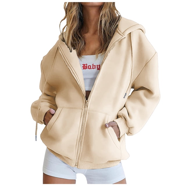 RKSTN Women's Zip Up Y2K Hoodies featuring a long sleeve, oversized fit, and solid beige color. This casual sweatshirt includes a full zipper, hood, kangaroo pockets, and ribbed cuffs and hem. Made from a polyester-spandex blend, it offers lightweight comfort suitable for fall and winter. Styled with a cropped tank top and shorts, ideal for casual outings or lounging.