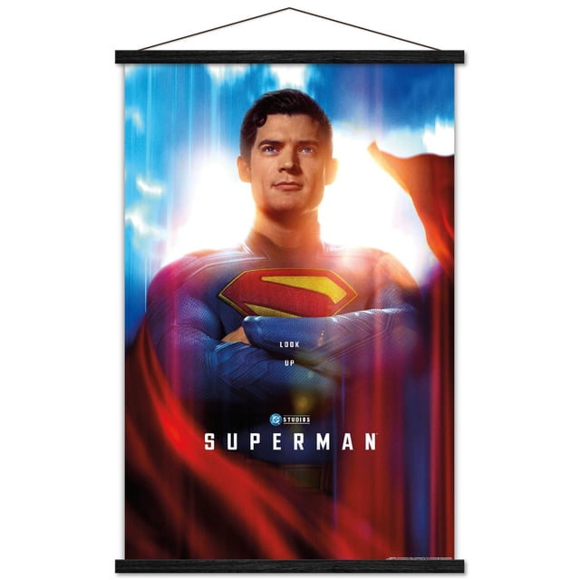 DC Studios Superman (2025) - Affiche Murale Gros Plan d'Une Feuille avec Cadre Magnétique Montrant un Gros Plan Centré et Orienté vers l'Avant de Superman en Costume Texturé Bleu avec un Emblème « s » Rouge et Jaune sur la Poitrine, les Bras Croisés, et une cape Rouge Fluide contre un Ciel Lumineux avec des Nuages, Mettant en Vedette le Texte « Regarde en L'air » et « Superman » avec le logo DC Studios, Idéal pour Ajouter une Déco Murale Audacieuse aux Chambres