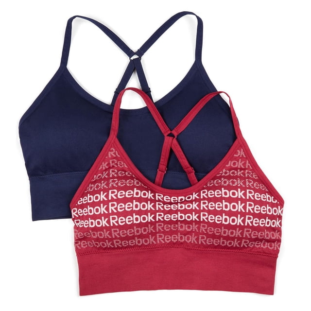 Reebok Ladies' 2 Pack Seamless Longline Bralettes including one solid navy blue and one red bralette with repeated white Reebok logos, both featuring adjustable racerback straps, longline bands for a smooth fit, and stretch fabric suitable for yoga, training, or casual wear.