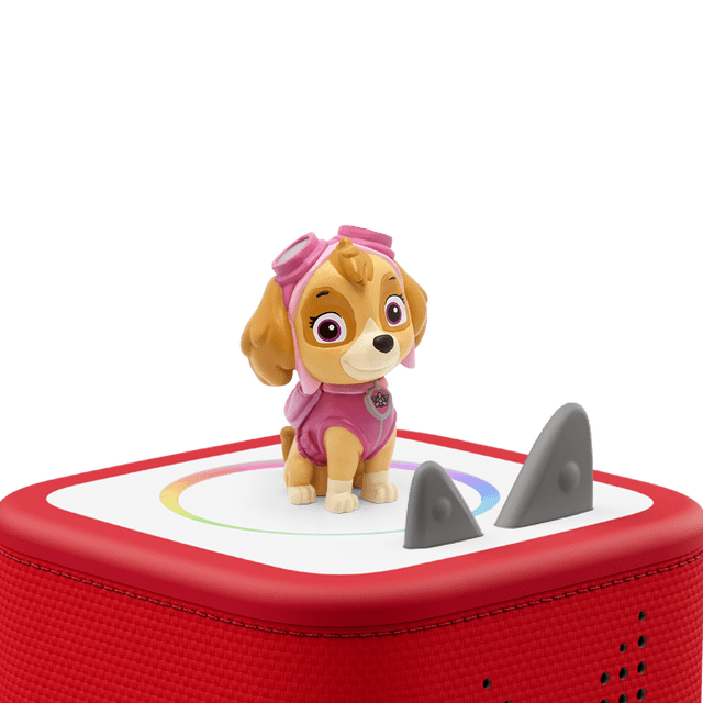 Tonies - LA PAT' PATROUILLE STELLA SYKE FIG (FRENCH ONLY) showing a multicolour figurine of Stella from PAW Patrol in pink pilot goggles and vest, standing on a red Toniebox audio player with a white top and circular color ring, designed for screen-free French storytelling for kids ages 3 and up.