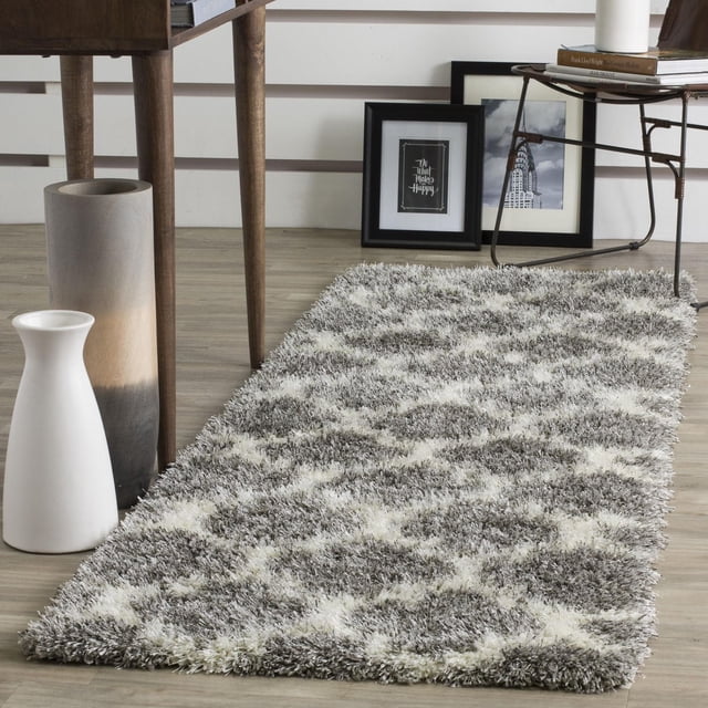 Safavieh Montreal Lennart Geometric Shag Area Rug featuring a plush gray and white geometric pattern with varied yarn density for texture and tonal depth on a light wood floor. Ideal for contemporary or transitional interiors, it is shown with modern decor including a wooden table, gradient ceramic vase, and framed art. Suitable for adding warmth and texture to hallways or living rooms.
