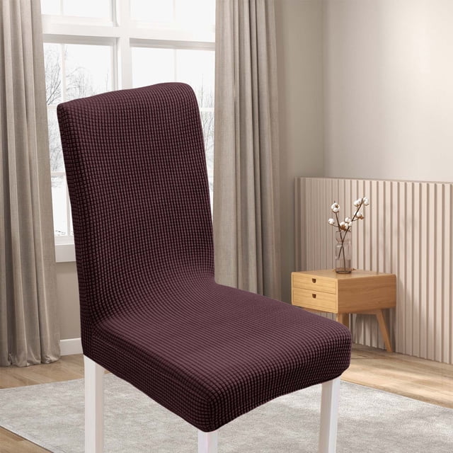 Trending dining room chair cover in a colorful D-599 design, made of elastic polyester material. This washable chair protector features a stretchable fit for most kitchen and dining chairs, offering protection against stains, wear, and scratches. Displayed in a modern dining room setting with neutral decor.
