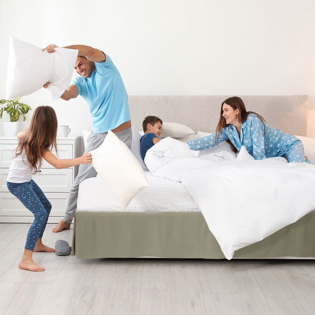 PiccoCasa Brushed Pleated Bed Skirt with a 16-inch drop in olive green, tailored to conceal box springs and under-bed storage. Made of 100% microfiber polyester, wrinkle-free and dust-resistant, shown on a queen-sized bed in a bright, modern bedroom setting. Easy to install with an adjustable elastic band.