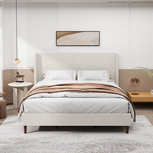 Noble House King Size Upholstered Bed Frame with High Headboard in beige chenille fabric, featuring 12 wooden slats for support and solid wood legs. The bed is front-facing with white bedding and a light brown throw in a modern bedroom with neutral tones, a round side table with a horse figurine, and a mustard nightstand with a glass lamp. Minimalist wall art hangs above the headboard.