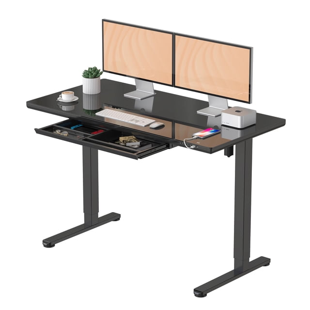 Electric height adjustable standing desk with a black tempered glass tabletop, ergonomic design, featuring a drawer, Type-C and USB ports, and a button control panel. The desk supports up to 50kg/110lbs and measures 47.2 x 23.6 inches. It is shown with dual monitors, a keyboard, a mouse, and accessories stored in the drawer.