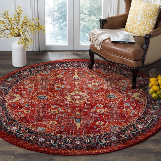 Safavieh Tapis Traditionnel Vintage Hamadan en Vinal, Rond avec une base Rouge et des motifs Floraux Persans Complexes en Bleu, Jaune et Crème, Posé sur un Plancher de Bois Franc Foncé Près d'Un Fauteuil en Cuir Brun avec un Coussin à Motif Jaune et un vase Blanc avec des Fleurs Jaunes Près d'Une Fenêtre Éclairée par le Soleil, Souvent Utilisé comme Tapis d'Accent Décoratif.