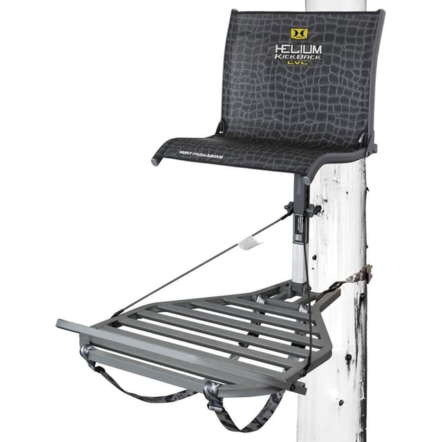 Hawk HF2033 Helium Kickback LVL Steel Hang-On Tree Stand with a contoured mesh comfort lounger seat for zero-pressure comfort and an oversized grip-mesh platform for stability. Features a footrest for leg extension, heavy-duty steel construction, and Tree Digger teeth for secure bark grip. Ideal for hunting and game management, with silent attachment hooks and PTFE washers. Black finish with platform dimensions of 26.5 x 31.5 inches and seat dimensions of 18 x 14 inches.