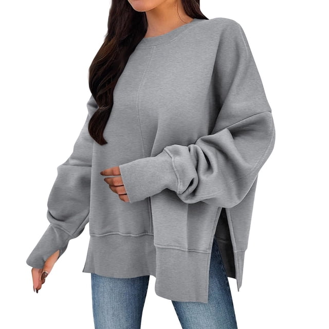 Timegard Oversized Sweatshirt for Women Thumb Hole Side Split Pullover Fall Loose Long Sleeve Tops. This grey oversized sweatshirt features a relaxed fit with long sleeves, thumb holes, and side splits for added style and comfort. Made from soft, breathable fabric, it is ideal for fall and winter wear. The model pairs it with blue jeans, showcasing its casual and versatile design.