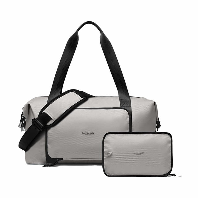 Gaston Luga Lightweight Packable Duffel Bag in taupe with black handles and adjustable shoulder strap, shown with its compact foldable pouch, made from eco-friendly recycled polyester with two outer zipped pockets and slip-over luggage strap, suitable for gym use and short trips.