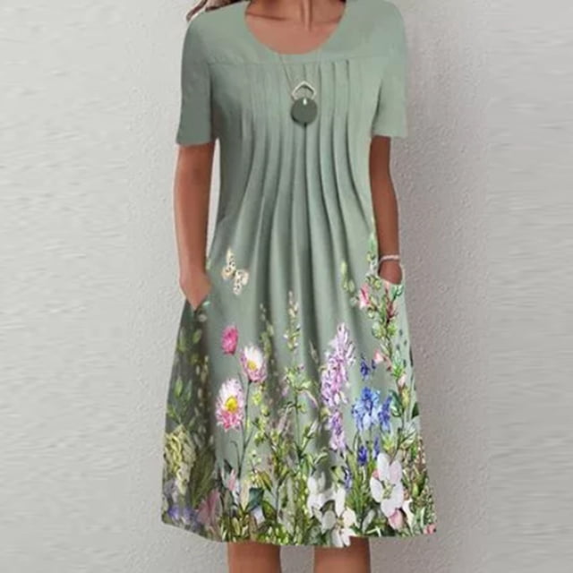 CEHVOM Robes de Plage Grande Taille pour Femmes avec un design à Manches Courtes, une Encolure Ronde et un Imprimé Graphique floral. la Robe Est Présentée dans un Ton Vert Doux avec des Détails Plissés sur le Corsage et des Motifs Floraux Vibrants à l'Ourlet. Fabriquée en polyester, Elle Offre une Coupe Décontractée et Confortable, Idéale pour les Sorties de Printemps et d'Été. le Modèle Est Accessoirisé avec un Collier Pendentif, et la Robe Comprend des Poches Latérales pour une Fonctionnalité Accrue.