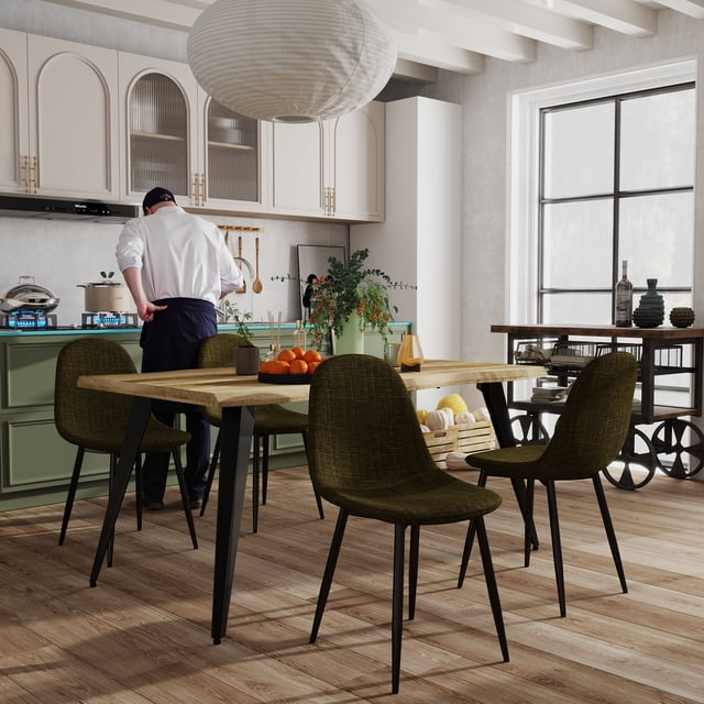 Homy Casa set of 4 modern dining chairs with green fabric upholstery and anti-rust black metal legs around a wooden dining table in a kitchen with green lower cabinets and white upper cabinets, featuring a chef cooking at the stove and natural light from a large window, suitable for compact kitchen seating.