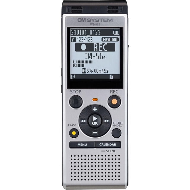 Système OM WS-882 Enregistreur Vocal Numérique avec Corps Rectangulaire Argenté et Dessus Noir, Doté d'Un Écran LCD monochrome Affichant l'Heure d'Enregistrement et des Informations sur les Dossiers. Il Comprend des microphones Stéréo, des Boutons de Commande Circulaires pour Arrêter, Enregistrer, Effacer, le menu et le Calendrier, un Haut-Parleur Intégré et une Longue Autonomie, Idéal pour les notes, les Entrevues et les Réunions.