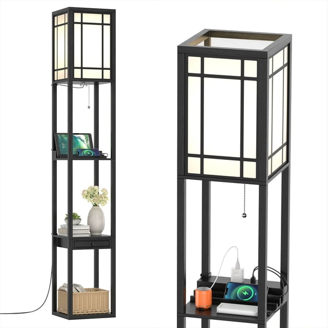 Gymax Modern Standing Shelf Floor Lamp with 1 power outlet and 2 USB ports, featuring a black MDF frame with a white lamp shade. The lamp includes three open shelves, a practical drawer with a handle, and a pull-switch chain for easy operation. The top shelf has an indentation for holding devices while charging. Suitable for living rooms or bedrooms, this vertical lamp combines lighting and storage functionality.