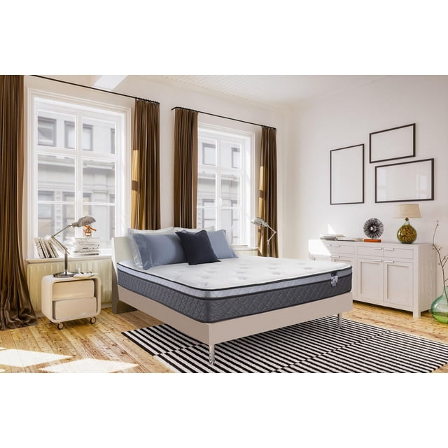 Springwall CHELSEA 9" Medium Plush Euro Top Pocket Coil Mattress in a box in a bright bedroom with wooden floors, featuring a white quilted top and dark grey sides with comfort pocket coils, on a beige platform bed with chrome legs, styled with blue and dark grey pillows, flanked by silver reading lamps, brown curtains framing large windows, and a white sideboard with decor.