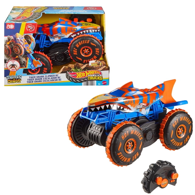 Hot Wheels Monster Trucks Tiger Shark Climber RC Vehicle, battery-powered remote-control toy truck in blue and orange with shark-themed graphics, large black and orange Grip Action Tires, and an extendable tail for climbing obstacles, shown with remote control and packaging.
