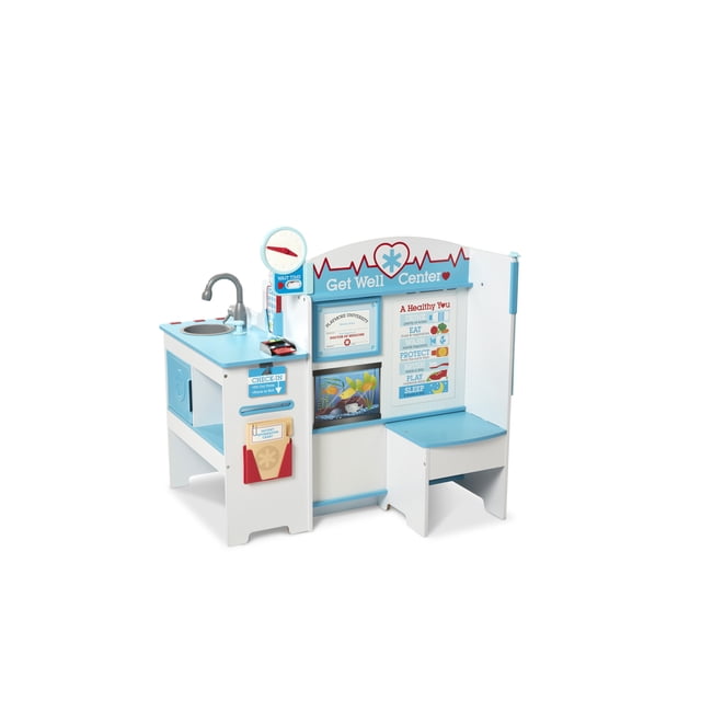 Melissa & Doug Wooden Get Well Doctor Activity Center featuring a multi-sided play space with a waiting area, exam room, sink, and reception area. Includes realistic details like a blood pressure monitor, X-rays, scale, eye chart, clock, and a credit card reader. Designed for imaginative play, it measures 35.5” x 37.25” x 21.25” and is made with FSC-certified materials.